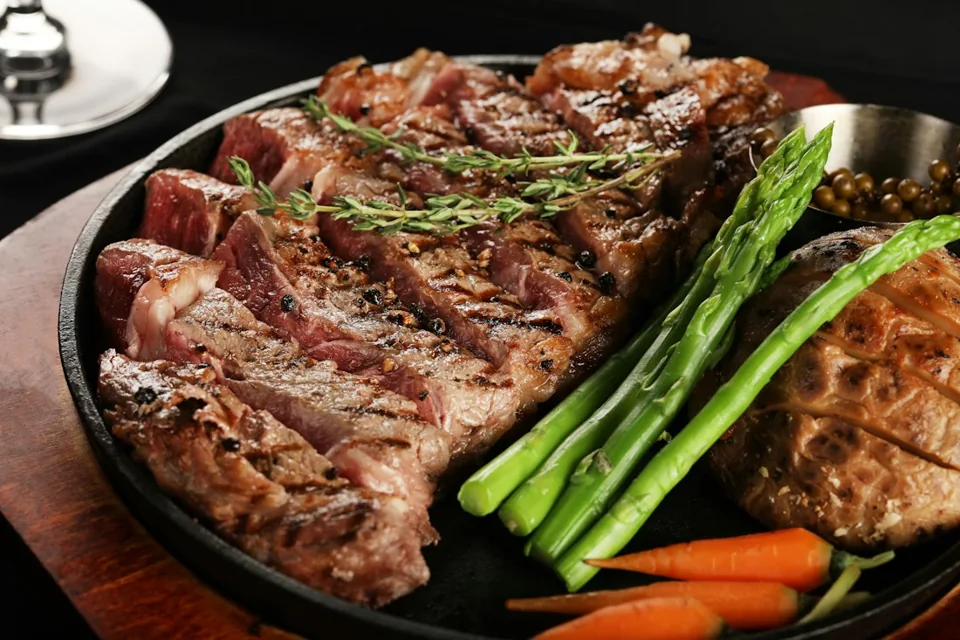Corte de carne servido con hierbas y vegetales